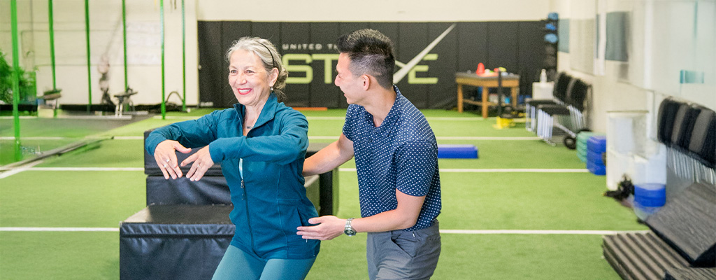 Post-Operative Physiotherapy in Winnipeg, therapist guiding older woman through supported squat exercise for strength and balance